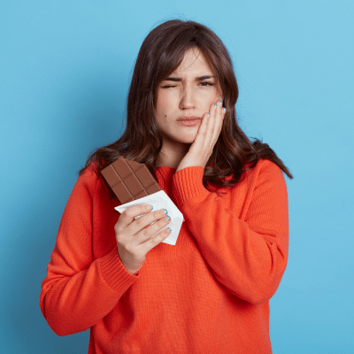 Woman holding jowl in pain, dealing with dental emergencies