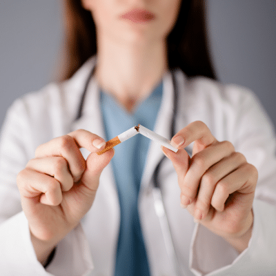 Female doctor breaking a cigarette in two, representing smoking and tobacco use