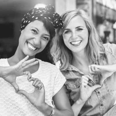 Two women making heart shapes with their hands, representing cosmetic dentistry