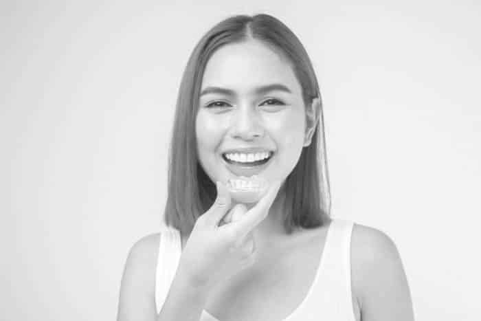 woman holding invisalign clear aligners outside of mouth