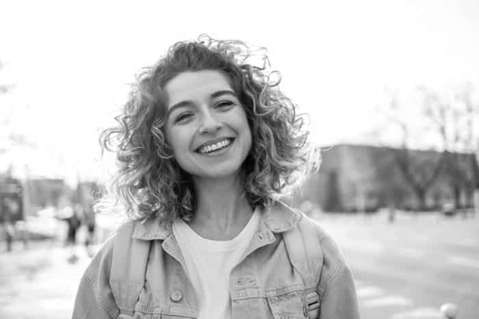 Fair Lakes Family Cosmetic Dentistry Young Woman Happy Outside implant dentistry