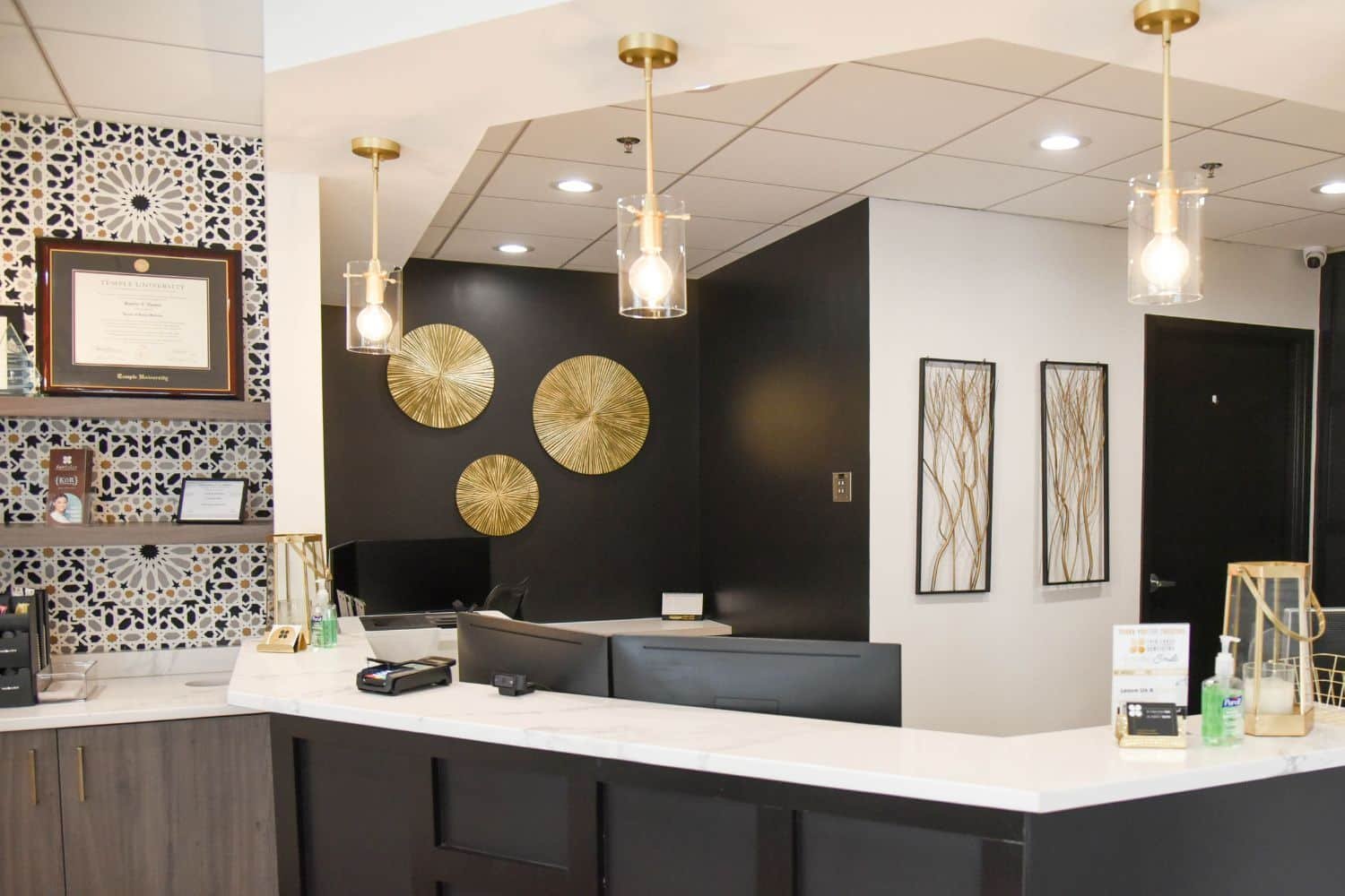 fair-lakes-cosmetic-dentistry-interior-entrance interior entrance with black receptionist desk and tile wall