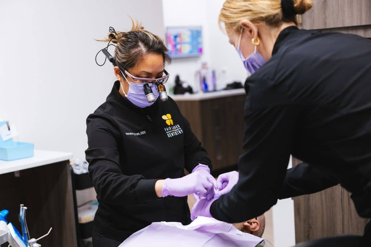 fair-lakes-family-and-cosmetic-dentistry (3) dr tran and blonde assistant working on male patient